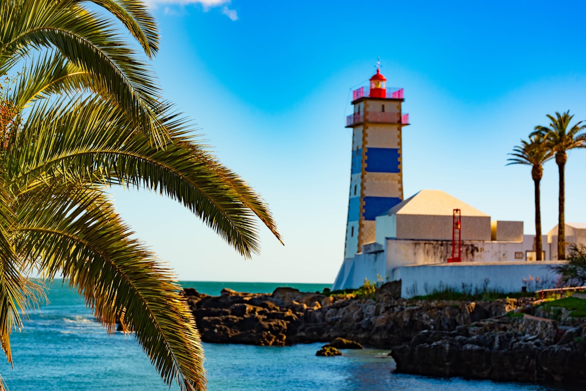Santa Marta lighthouse with blue and white stripes beside the Atlantic, Cascais, Portugal