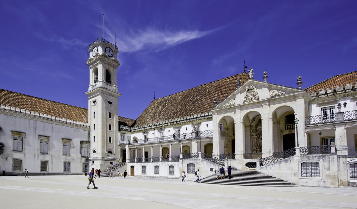 University of Coimbra courtyard with baroque clock tower against blue sky, Portugal