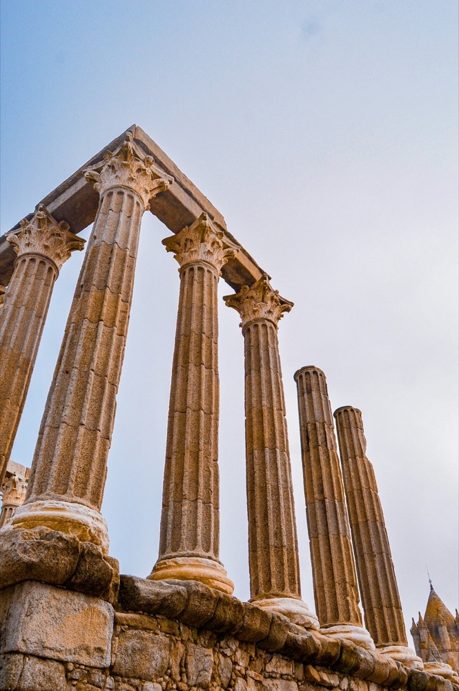 Roman Temple of Évora granite columns rising against a pale blue sky, Alentejo, Portugal