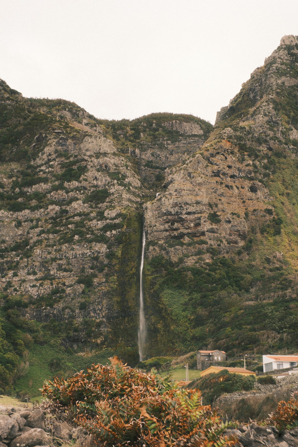 Tall slender waterfall descending a lush volcanic mountainside, Flores island, Azores, Portugal