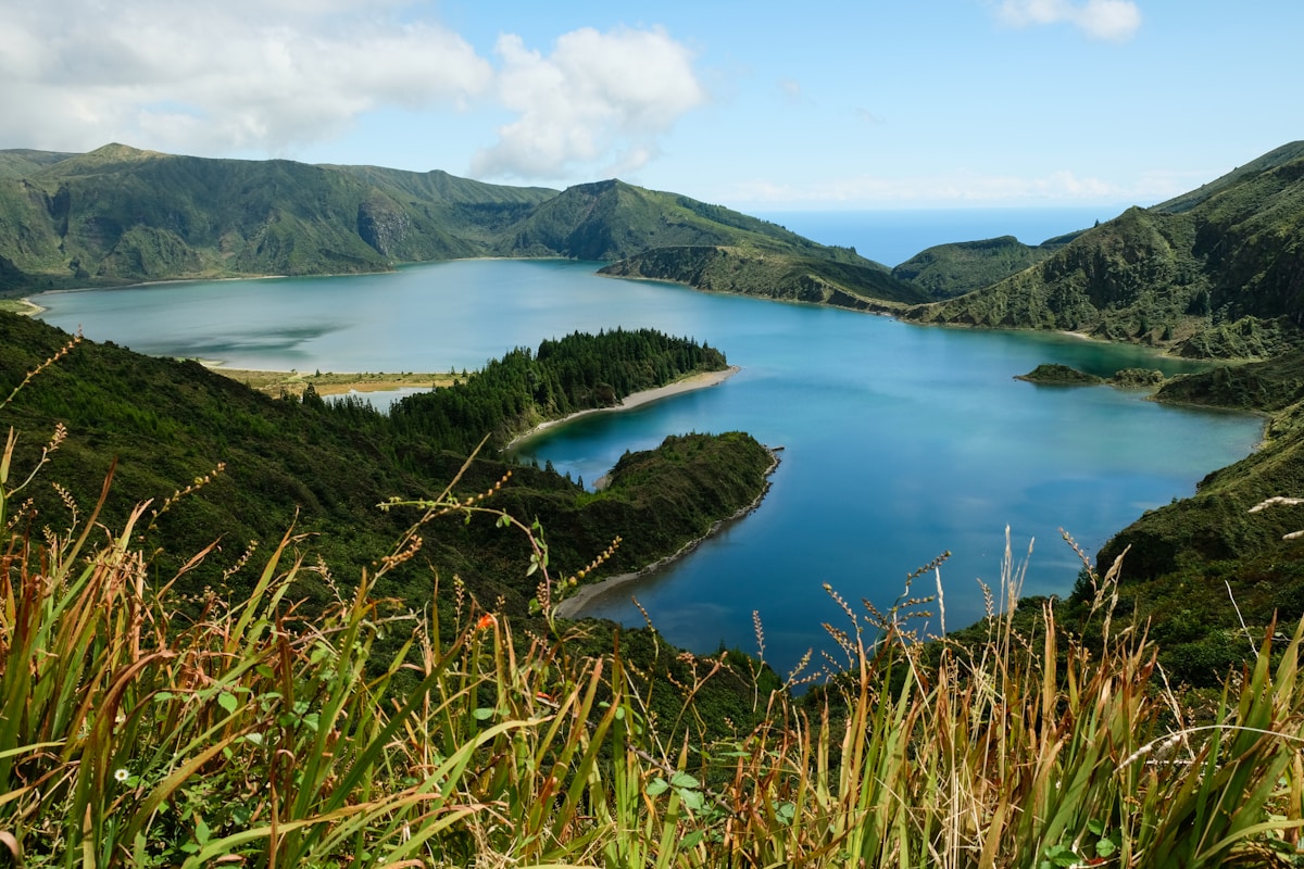 Volcanic crater lake surrounded by green hills under blue skies, Azores, Portugal