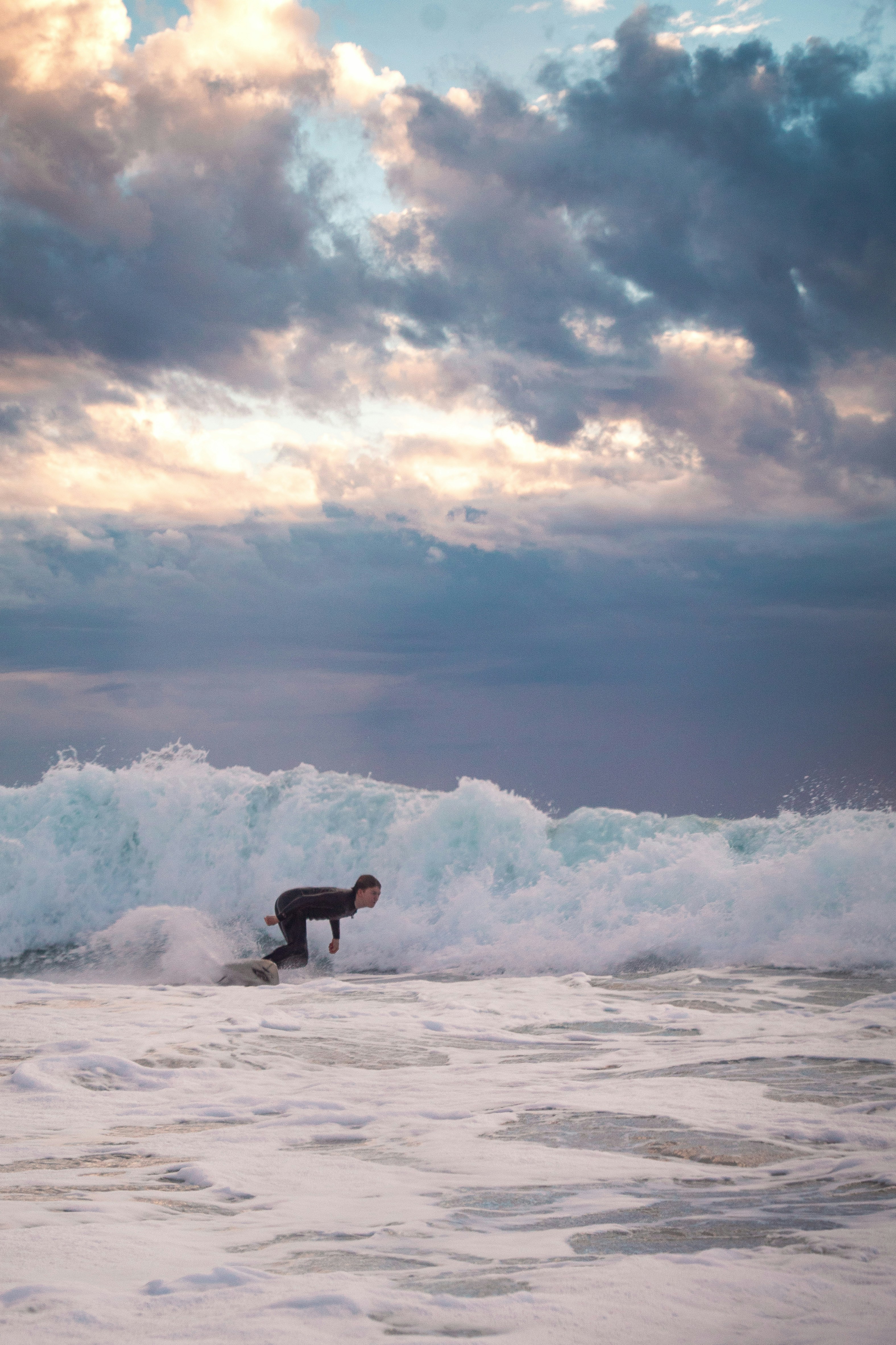 Surfer in a wetsuit practising on small whitewater waves on a Portuguese beach