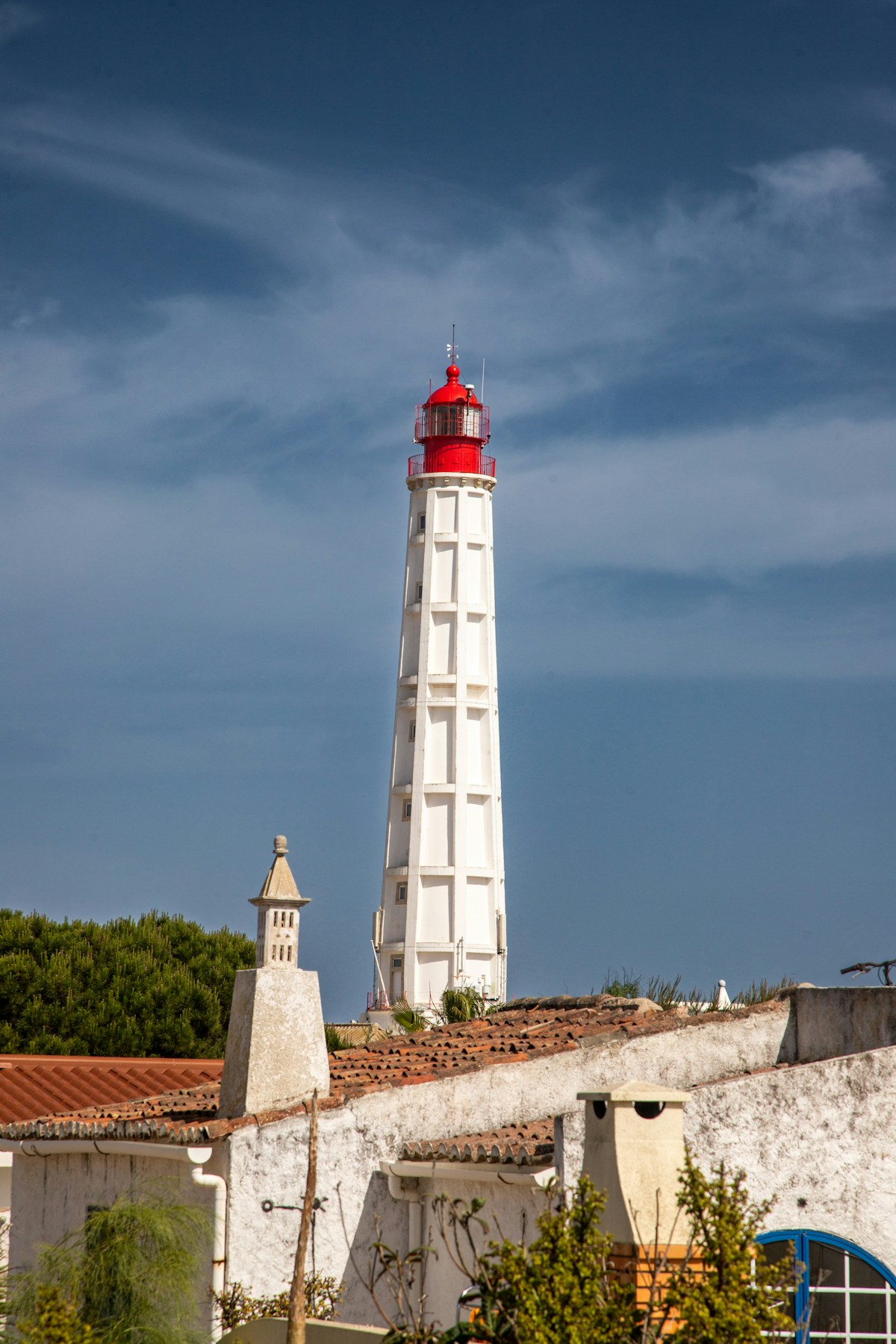 White lighthouse with red top on Ilha do Farol, Ria Formosa barrier islands accessible by ferry from Olhão, Portugal