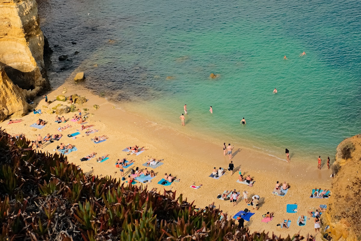 Turquoise water beach at Arrabida Natural Park near Setubal, with golden cliffs and sunbathers