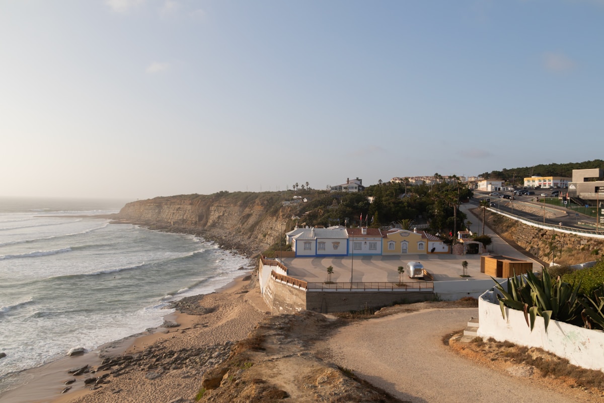 Coastal cliffs and surf beach below the whitewashed village of Ericeira, Portugal