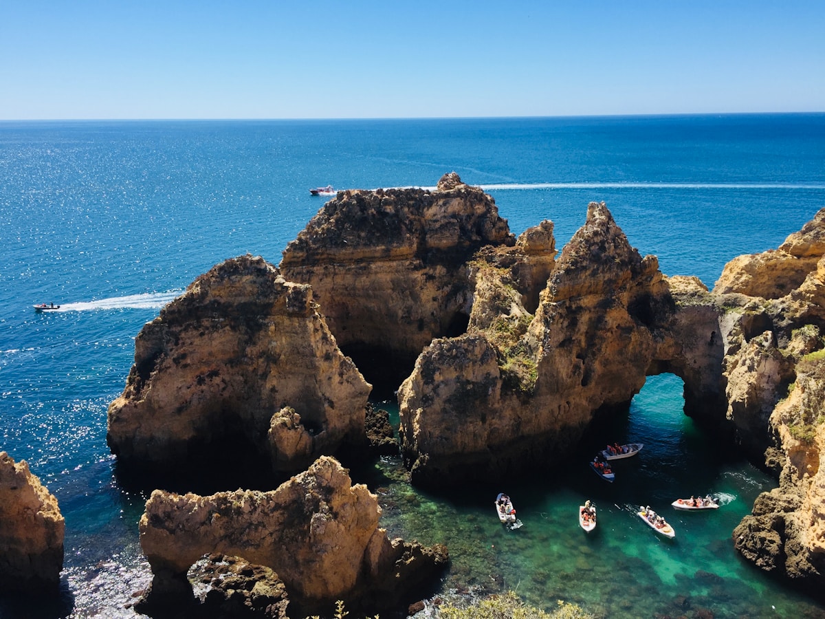 Boats and kayakers among the golden rock arches at Ponta da Piedade, Lagos, Algarve, Portugal