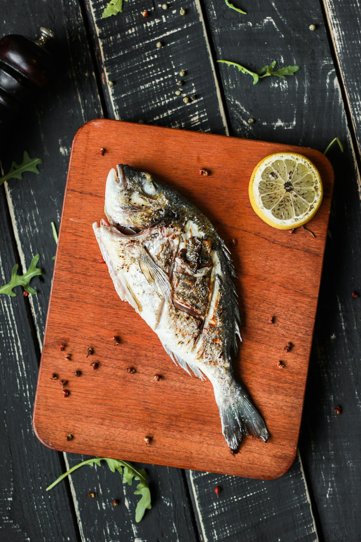 A whole grilled fish on a wooden chopping board with lemon, representing the central role of fish in Portuguese cuisine