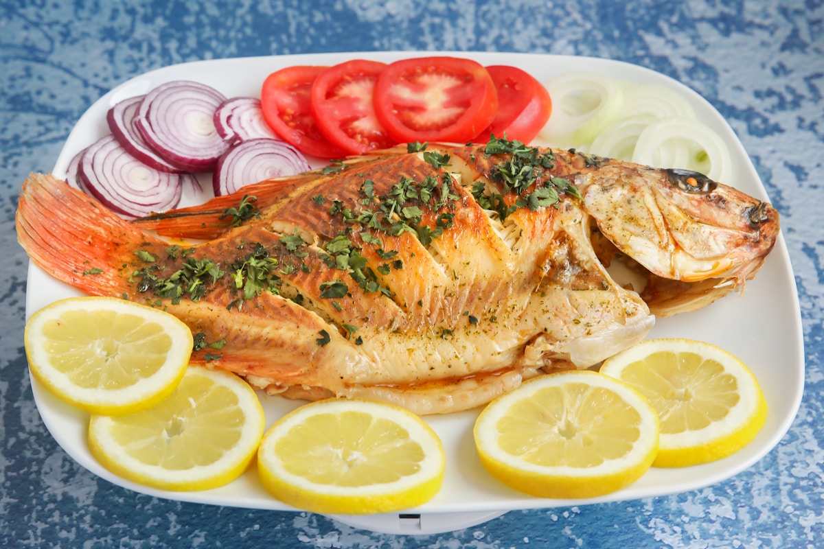 Grilled whole fish with lemon slices and tomatoes - fresh Atlantic seafood on Faial island, Azores