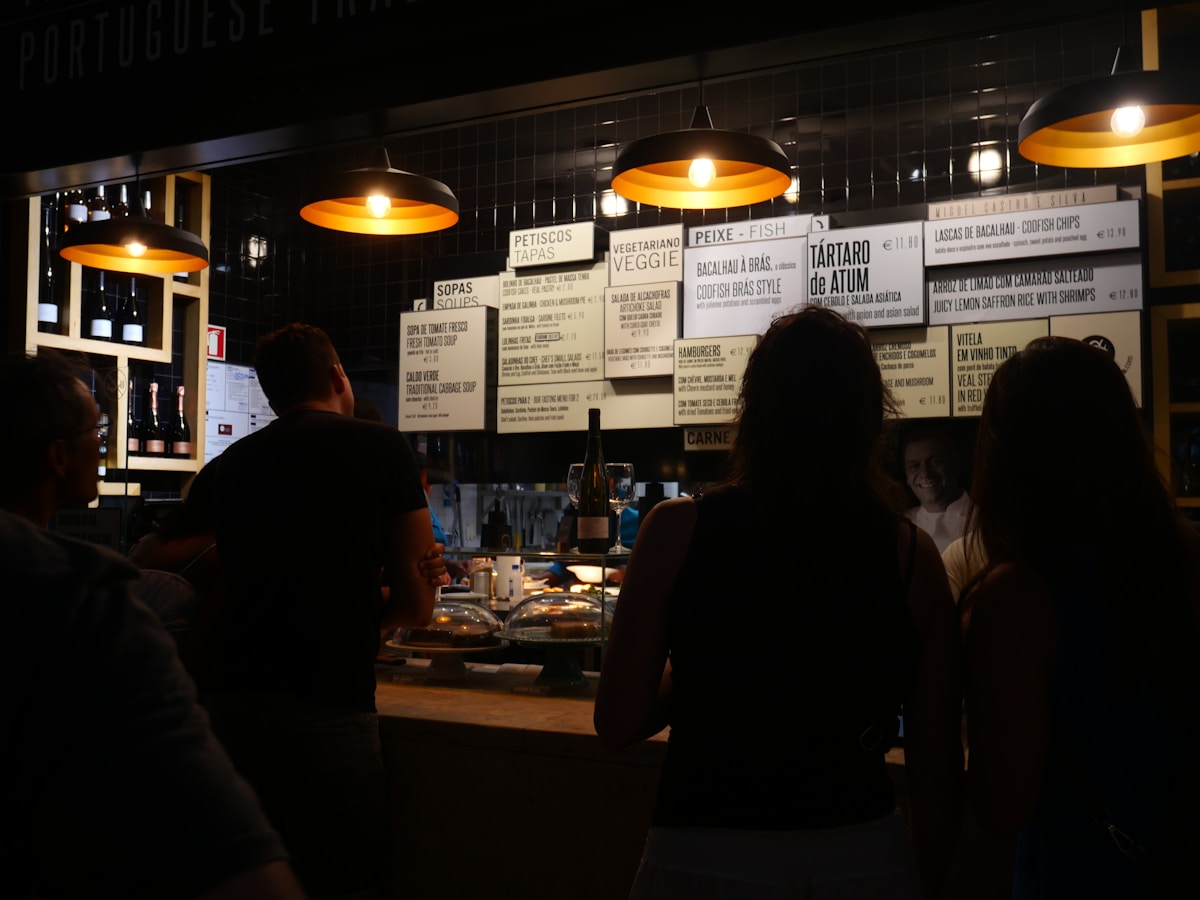 People dining at a Portuguese traditional restaurant in Lisbon with menu boards showing petiscos and bacalhau