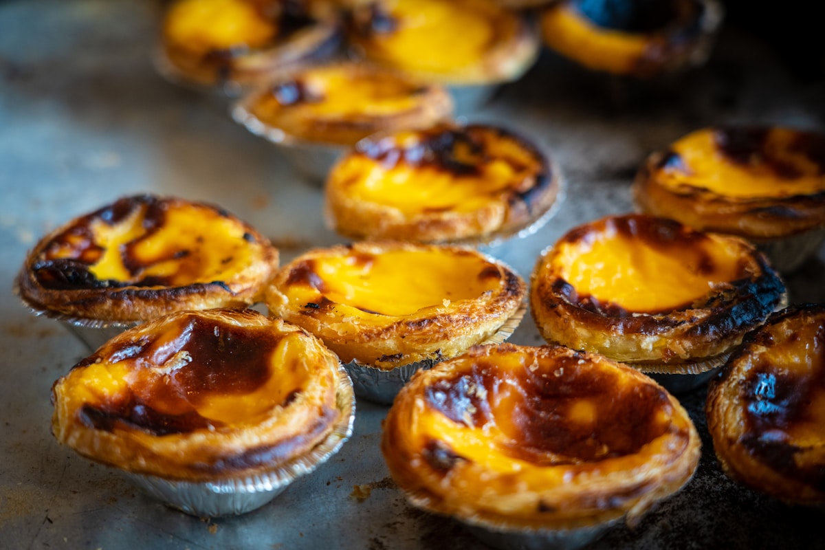 Golden pasteis de nata custard tarts fresh from the oven on a baking tray at a Portuguese pastelaria