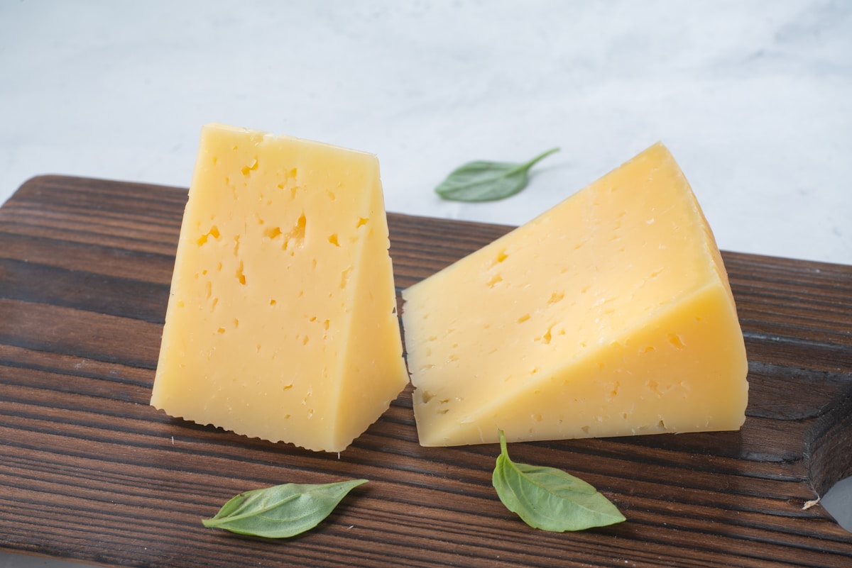 Wedges of aged hard cheese on a dark wooden board - Queijo São Jorge, the Azores' most famous cheese