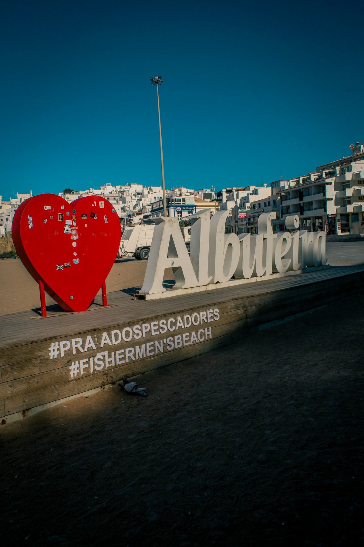 Albufeira sign on Fishermen's Beach boardwalk with white resort buildings rising behind, Algarve, Portugal