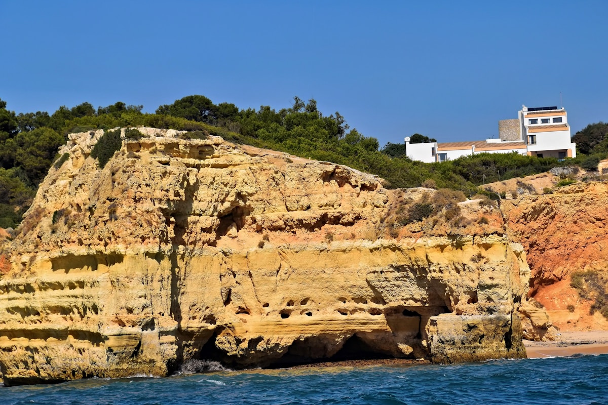 Golden limestone cliffs with a white villa perched above the Atlantic coast, Algarve, Portugal