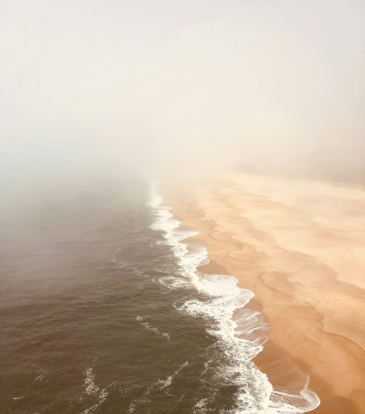 Enormous breaking wave at Praia do Norte Nazaré with a surfer on a tow-in board