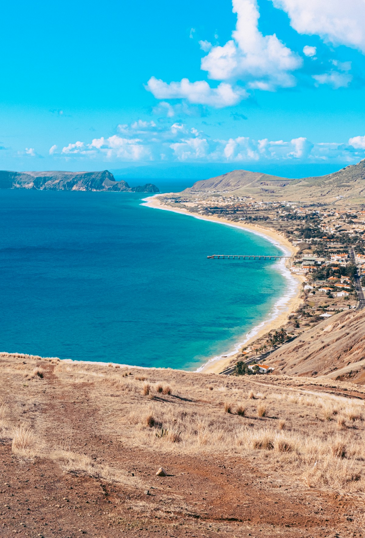 Aerial view of Porto Santo's 9km golden sand beach curving along the south coast, with the town and hills beyond, Porto Santo island, Madeira, Portugal