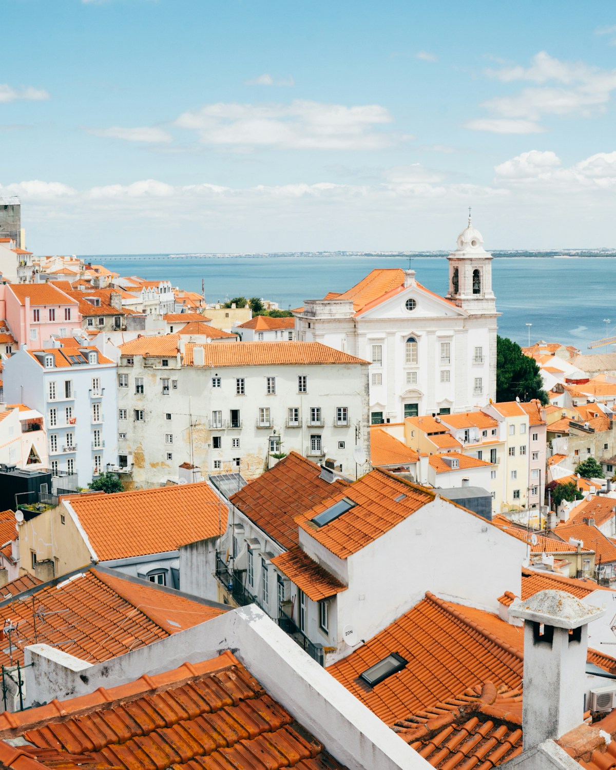 Orange terracotta rooftops and the Tagus river from Alfama, Lisbon
