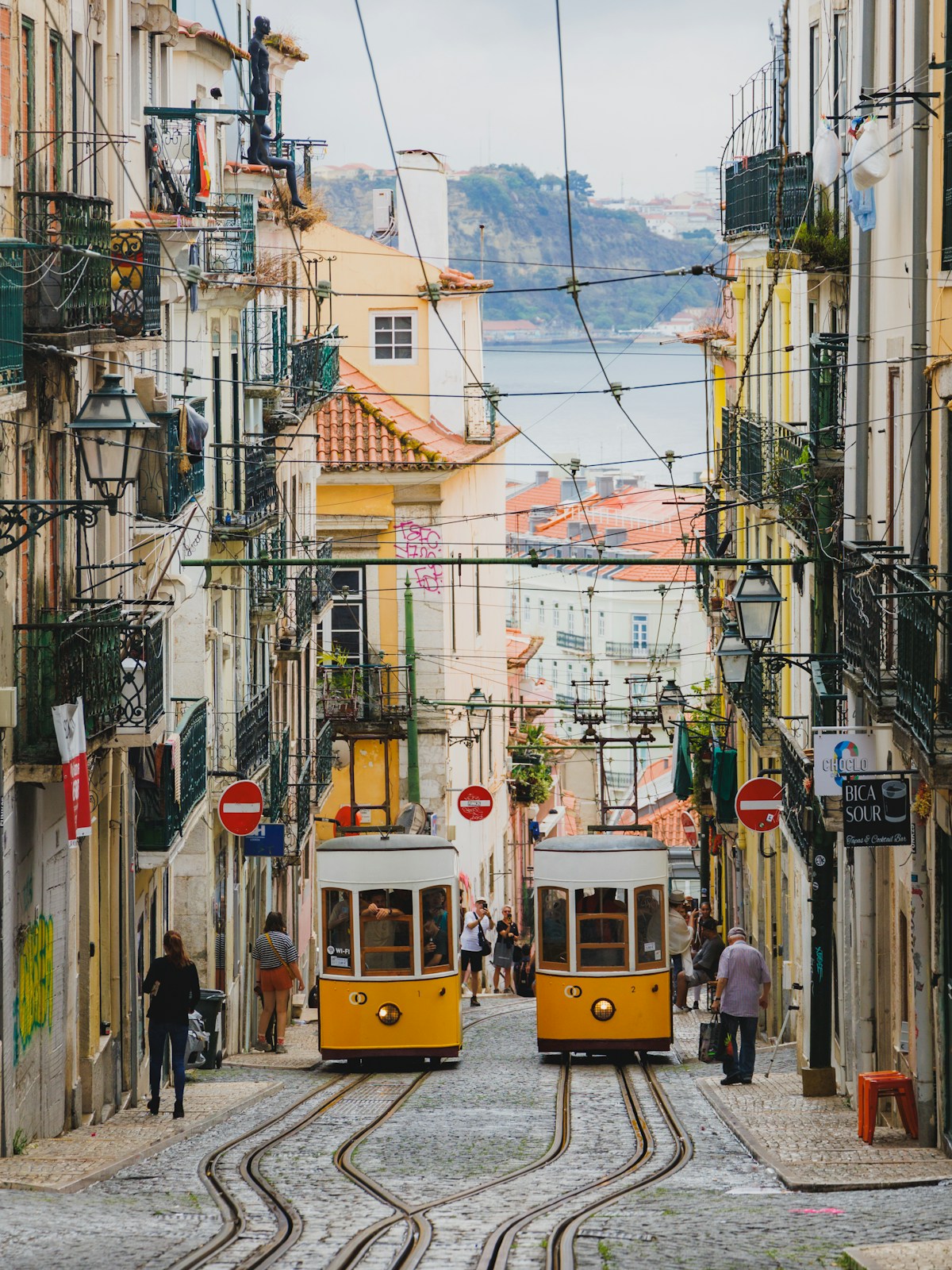 Two yellow trams on the steep cobblestoned streets of Lisbon's Alfama district