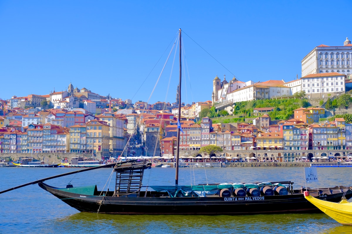 Traditional rabelo boat on the Douro River with colourful Ribeira buildings behind, Porto, Portugal