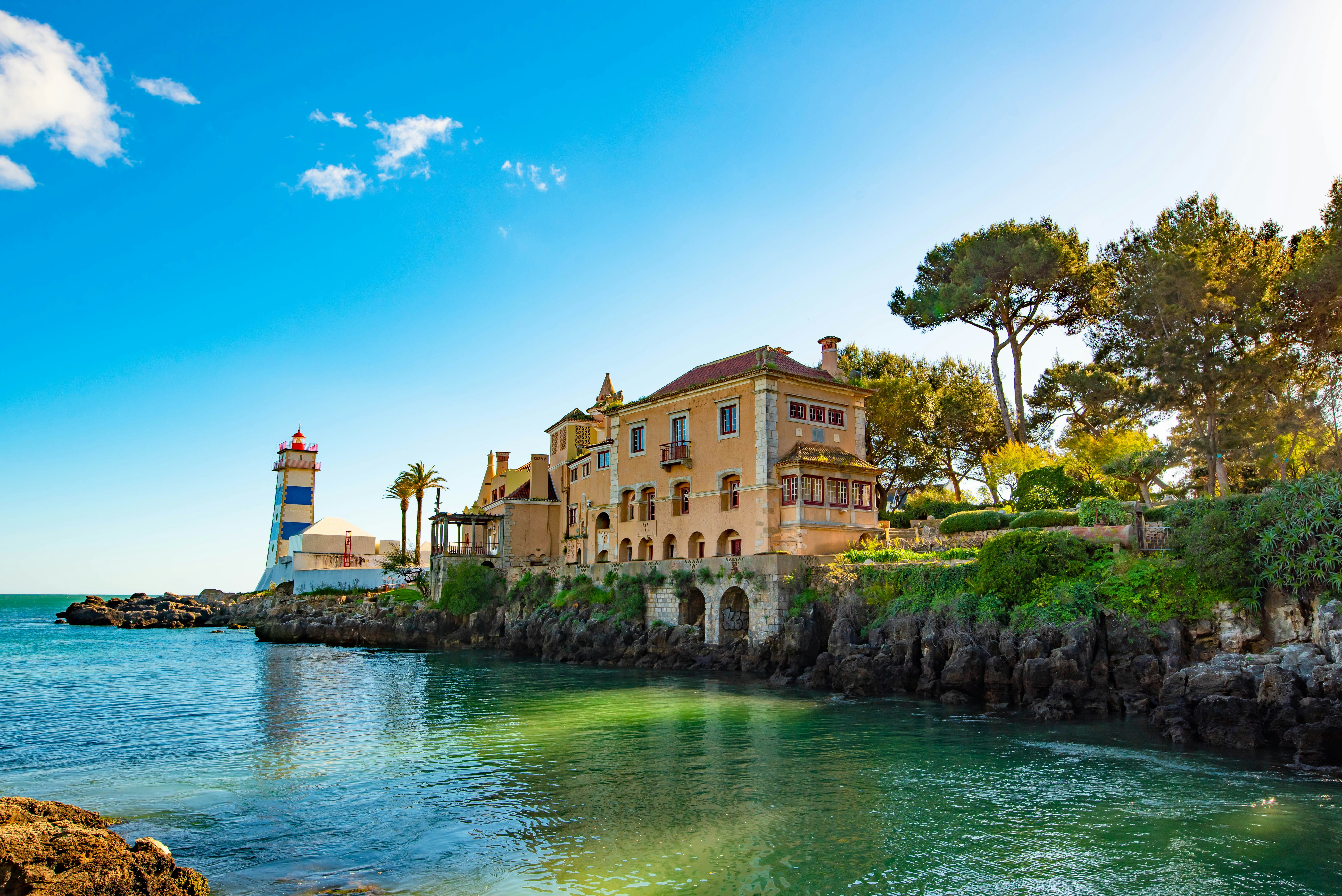 Santa Marta lighthouse and grand villa beside turquoise Atlantic waters, Cascais, Portugal