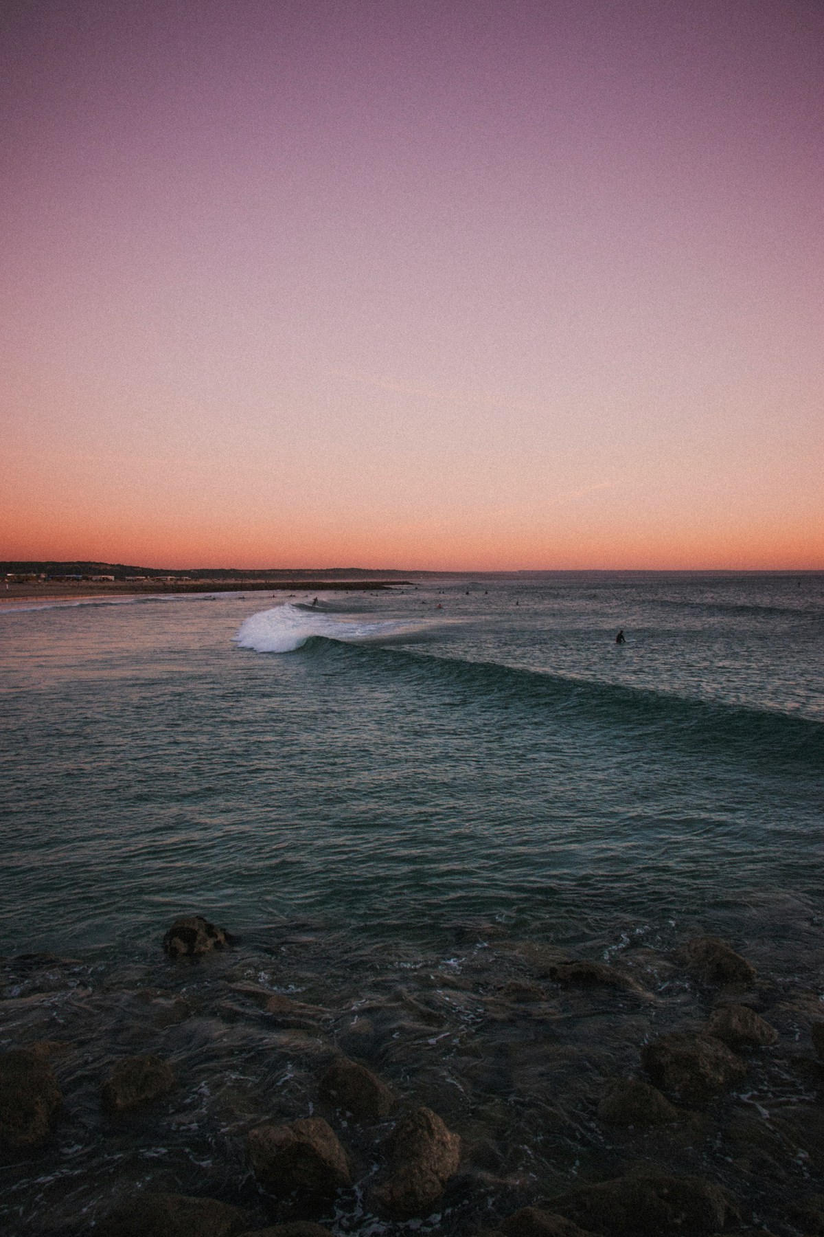 Surfer riding a wave at dusk on the beach at Costa da Caparica, south of Lisbon, Portugal