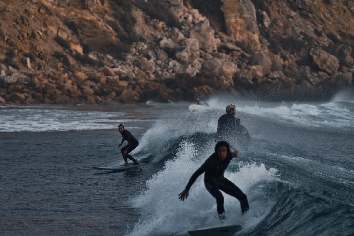 Surfers riding a wave at Praia do Zavial beach in the Algarve, one of Portugal's top surf spots