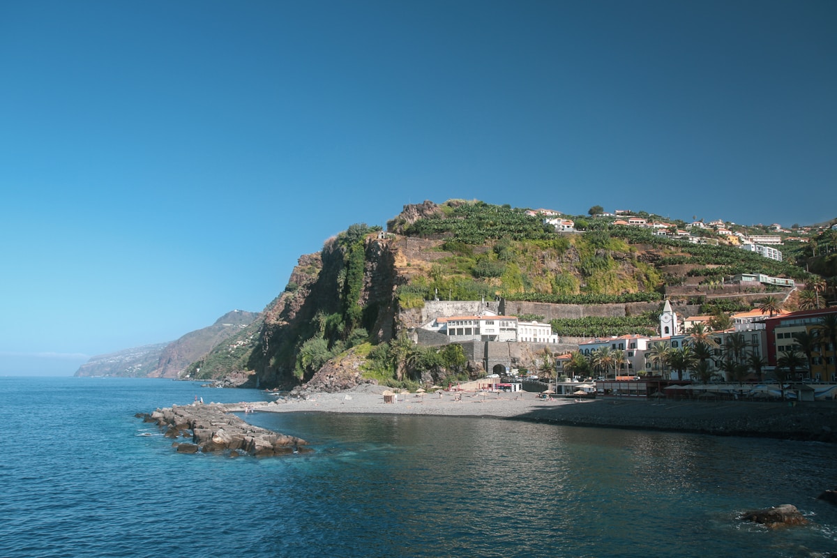 Coastal village of Ponta do Sol nestled at the base of green volcanic cliffs, Madeira, Portugal