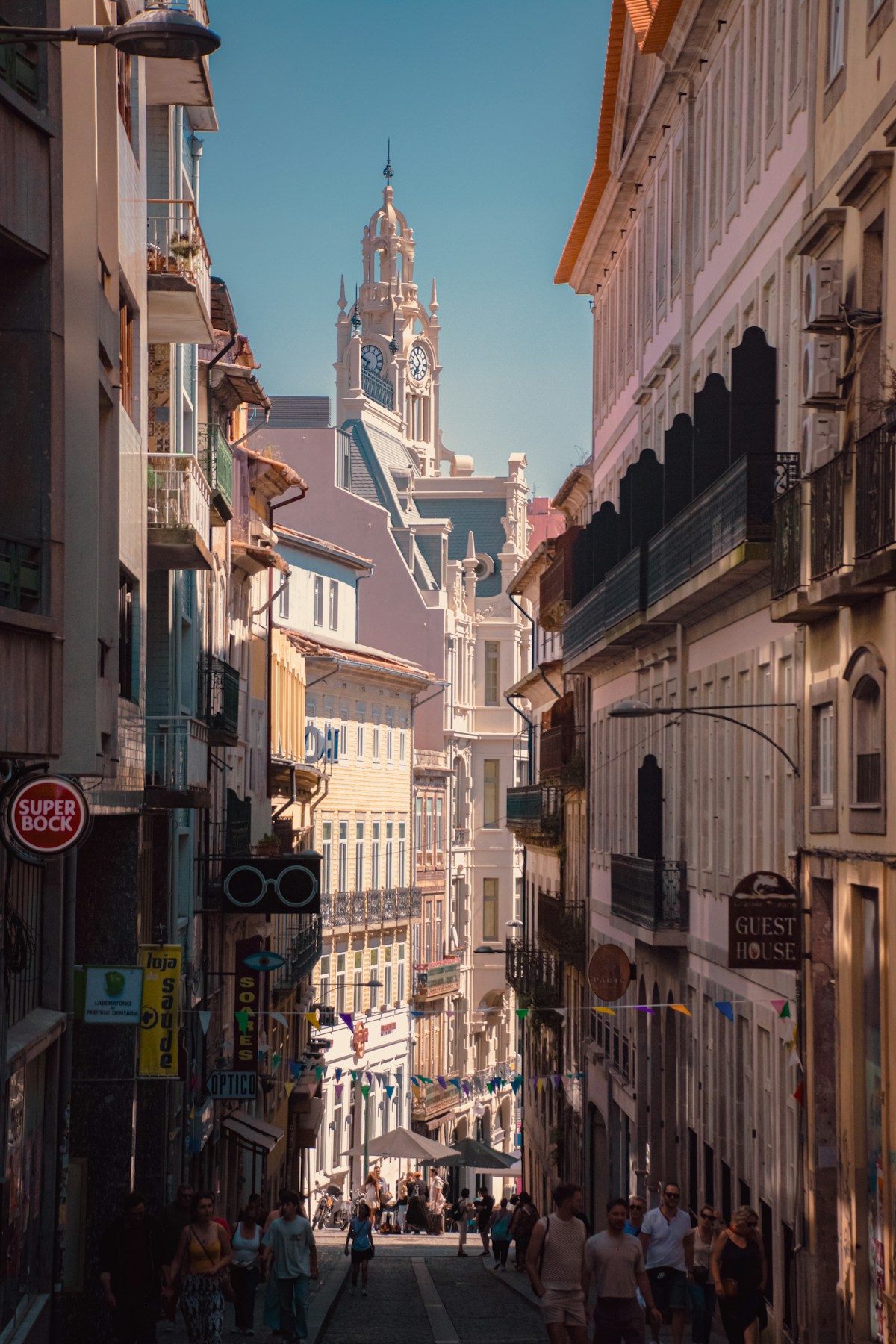 Bustling shopping street in central Porto with a clock tower rising above the buildings