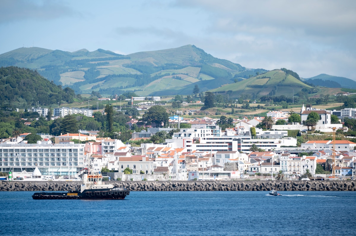 Ponta Delgada waterfront with city buildings and green volcanic hills, São Miguel, Azores, Portugal
