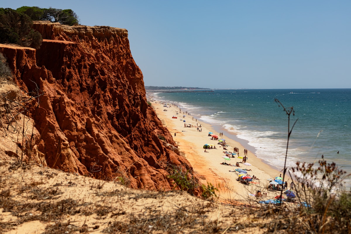 Long sandy beach with terracotta cliffs and sunbathers, Albufeira, Algarve, Portugal