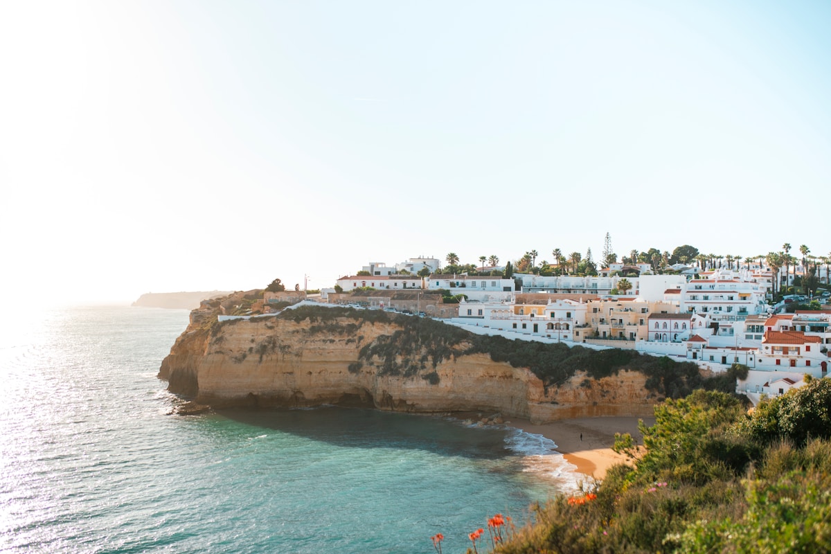 White Algarve village perched on golden limestone cliffs above a sandy cove at Carvoeiro, southern Portugal