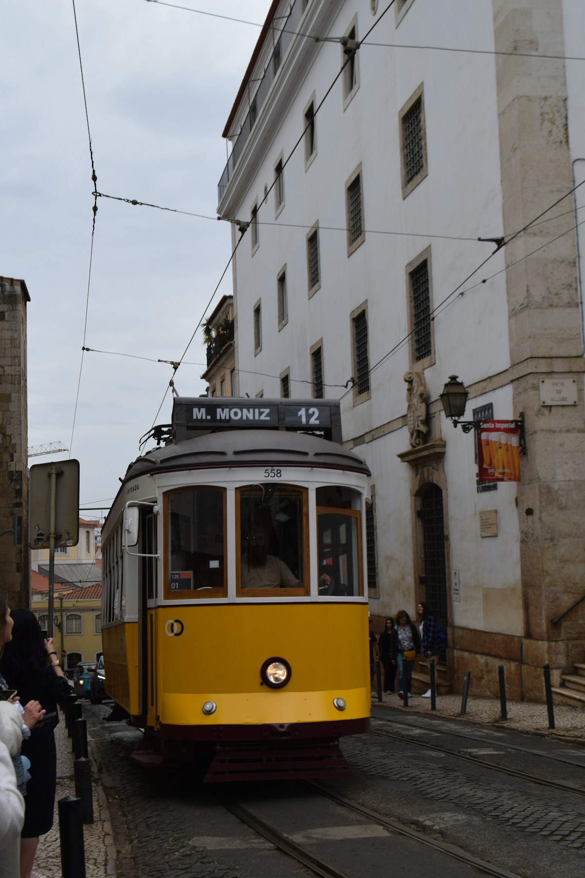 Yellow tram 12 travelling up a cobblestone street in Lisbon, Portugal